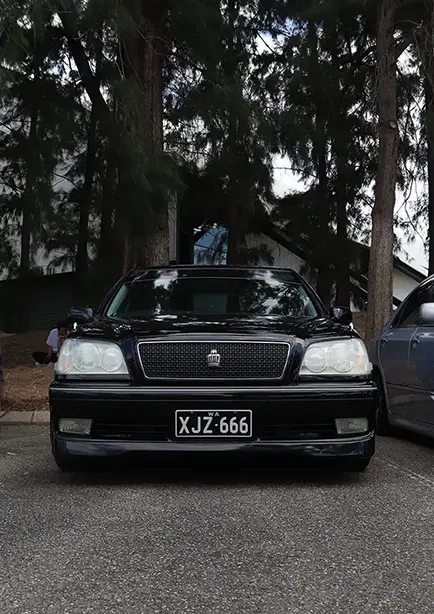 Front on shot of a black Toyota Crown in the forrest