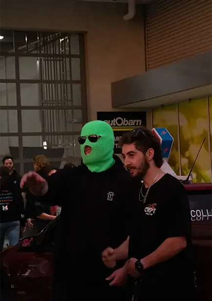 Man with a neon green ski mask named spotto taking a picture with a fan